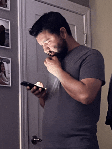 a man with a beard looks at his phone