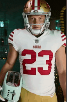 a man wearing a 49ers jersey holds a toaster
