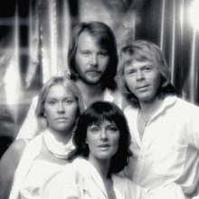 a group of four people posing for a photo in front of a silver curtain