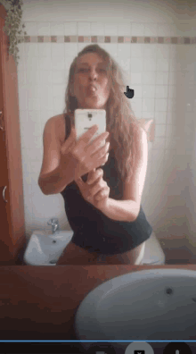 a woman taking a picture of herself in a bathroom with a samsung phone