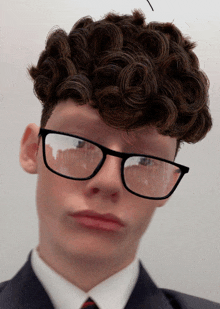 a man with curly hair wearing glasses and a tie