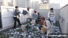 a group of young men are having a pillow fight on a rooftop with a christmas tree in the background