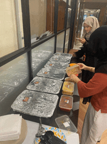 a woman reaches for a container of food that has a label that says ' chicken ' on it