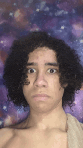 a young man with curly hair is making a funny face in front of a purple background