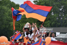 a crowd of people are holding flags and balloons during a soccer match .