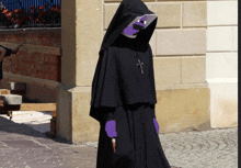 a nun wearing purple gloves and a black robe with a cross on it