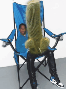 a man is sitting in a blue chair with a cactus on his back