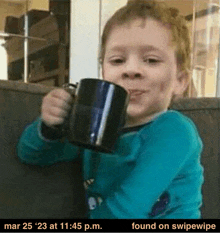 a young boy is sitting on a couch drinking from a mug