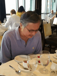 a man in a blue polo shirt sits at a restaurant table