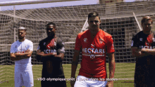 a group of soccer players are standing on a field and one of them is wearing a red shirt that says hectare