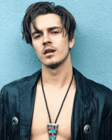 a shirtless man wearing a necklace and a leather jacket