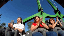 three people are riding a roller coaster and one of them is wearing a shirt that says ' abercrombie '