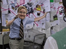 a man is standing in front of a bulletin board with a lot of papers on it .