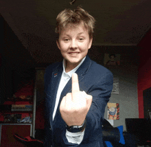 a young man in a suit and white shirt giving the middle finger