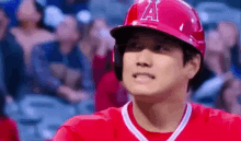 a baseball player wearing a red helmet and a red shirt is standing in front of a crowd at a baseball game .