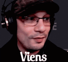 a man wearing headphones and glasses has the word viens written on his face