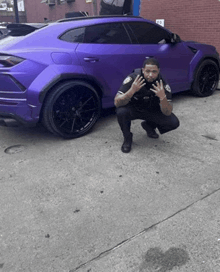a man in a police uniform squatting in front of a purple car