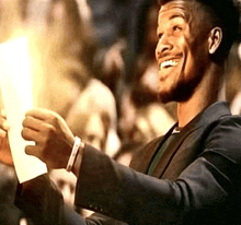 a man in a suit is smiling and holding a piece of paper in his hand