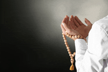 a person is praying with a wooden beads necklace