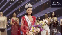 a woman in a red dress is holding a bouquet of flowers in front of a group of women .