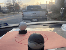 a ford truck is parked on the side of the road behind a ball