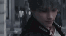 a close up of a person 's face with a blurry background and a man walking in the background .