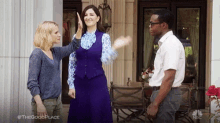 a man and two women are giving each other a high five while standing in front of a building .