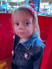 a little girl wearing a denim jacket has a soccer ball pin on her jacket