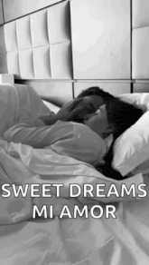 a man and a woman are laying in bed kissing .