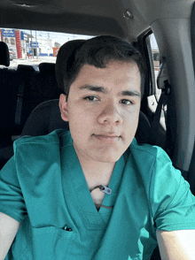 a young man in a green scrub top is sitting in a car