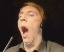 a man is yawning while wearing headphones and making a funny face .