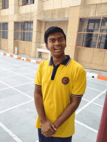 a young man wearing a yellow shirt with a sun logo on the front