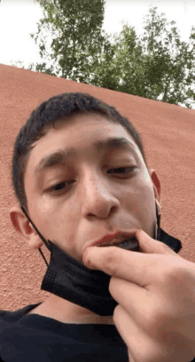 a young man wearing a black mask eating something