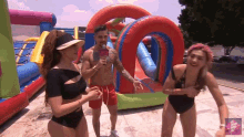 a man and two women are standing in front of a bouncy house and a sign that says " en espanol "