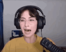 a woman wearing headphones and a yellow shirt is speaking into a microphone .