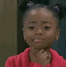 a little girl is making a funny face with her hand to her chin .