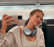 a woman wearing headphones is taking a picture of herself with her phone