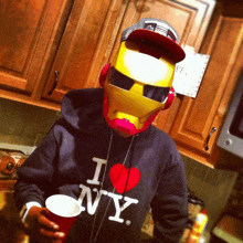 a man wearing a hoodie that says i love ny is holding a cup