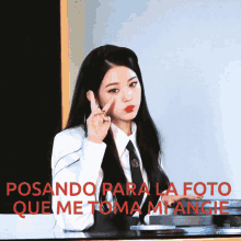 a woman in a white shirt and tie is making a peace sign in front of a sign that says rosando para la foto