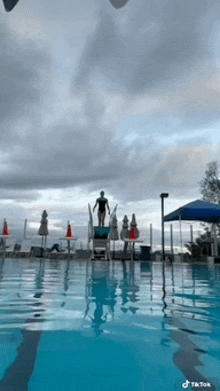 a person is standing on a diving board in a pool ..