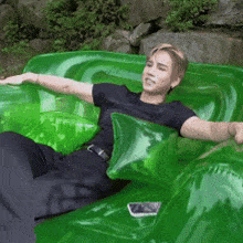 a man in a black shirt is laying on a green inflatable couch .