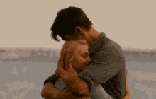 a man is holding a woman in his arms in front of a body of water .