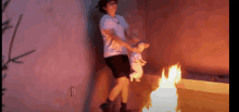 a woman is holding a baby in front of a burning fire .