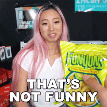 a woman with pink hair is holding a bag of funyuns candy .