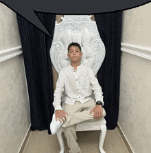 a boy in a white shirt is sitting in a chair