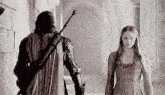 a man in armor is standing next to a woman in a dress .