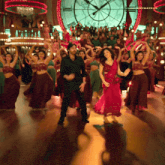 a man and a woman are dancing in front of a large clock that says mightymatelu