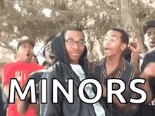 a group of young men are standing in front of a tree with the word minors written on the ground .