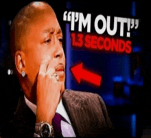 a man in a suit and tie is sitting in front of a sign that says " i 'm out "