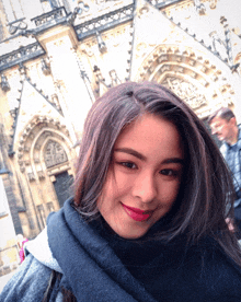 a woman wearing a scarf stands in front of a church